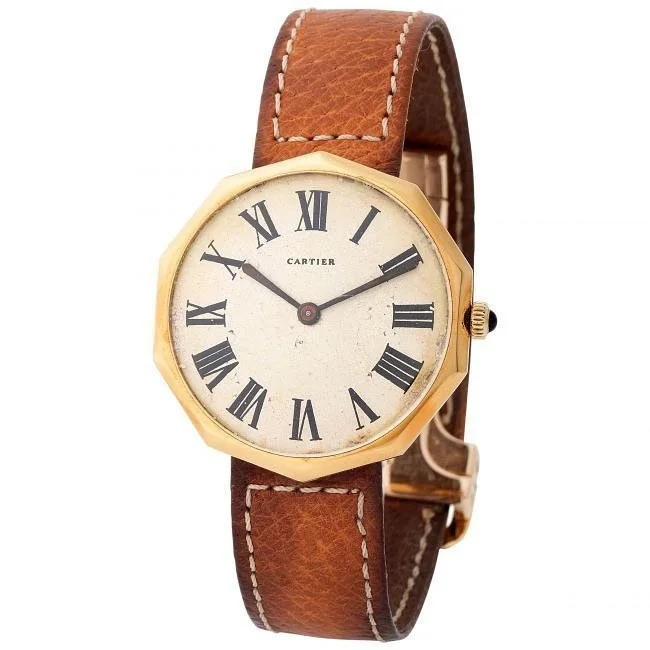 Vintage Cartier octagonal gold watch with cream dial, Roman numerals, and brown leather strap.