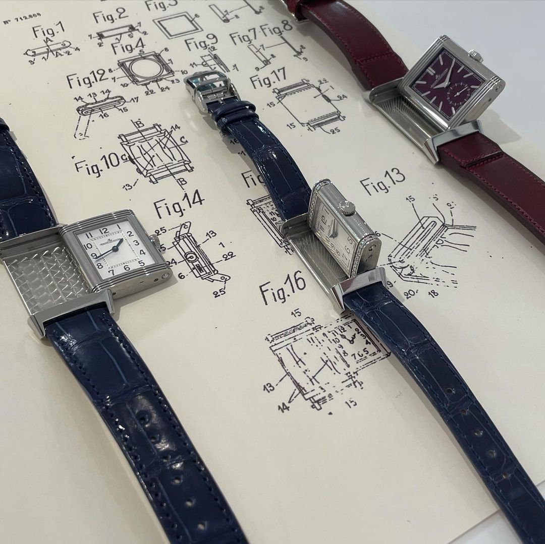 Three rectangular reversible watches with leather straps lie on a vintage patent drawing.