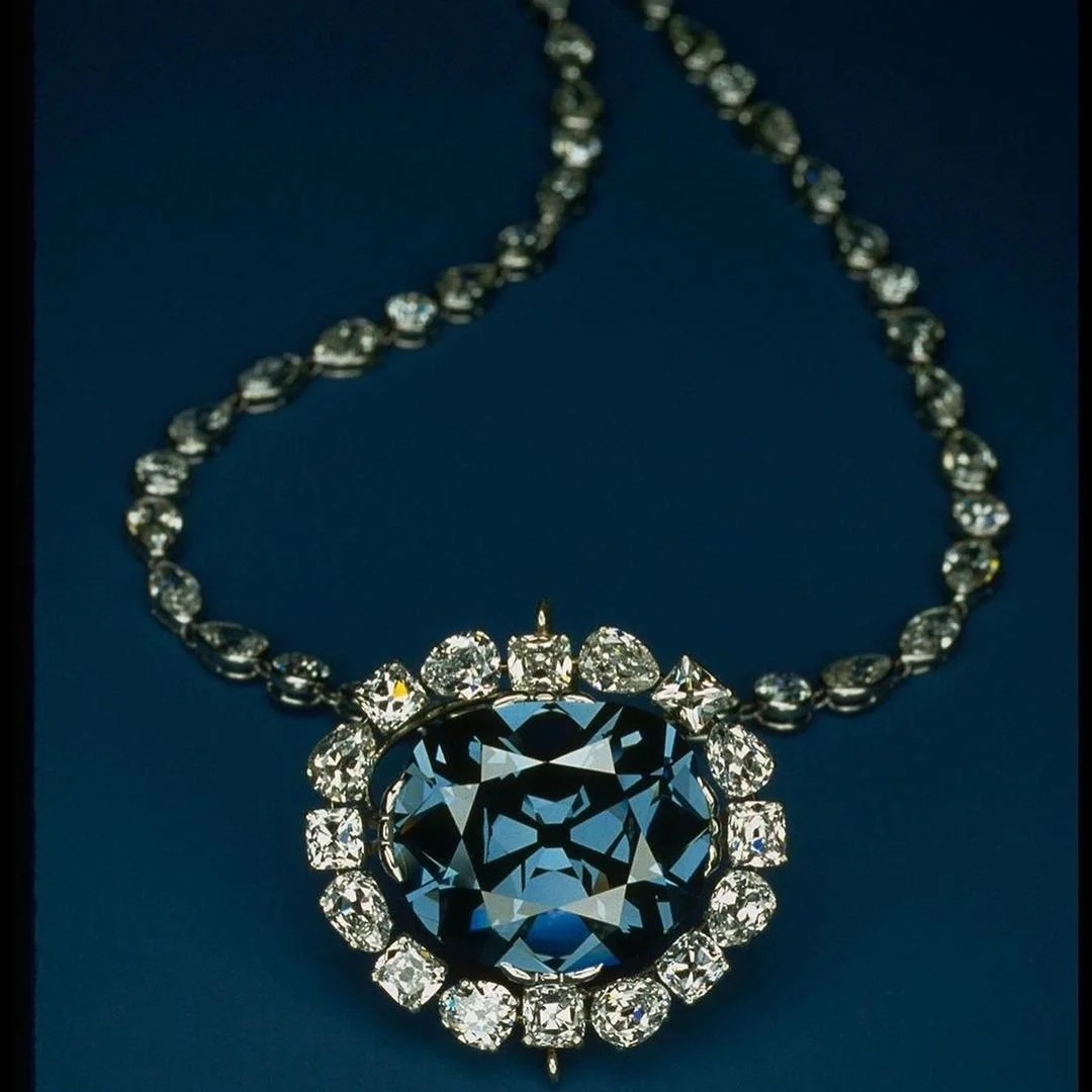 Large cushion-cut blue diamond pendant surrounded by white diamonds on a diamond necklace.