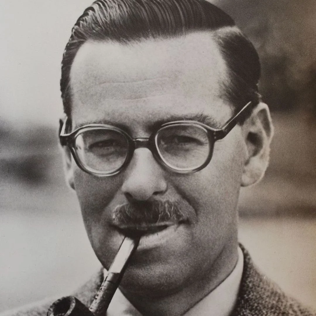 Black and white portrait of a man with glasses, mustache, and a pipe in his mouth.