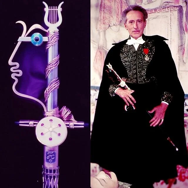 Academician in robes holds ceremonial sword with stylized face and lyre hilt.