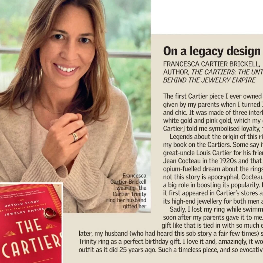 Smiling Francesca Cartier Brickell wears a three-band gold Cartier Trinity ring on her left hand.