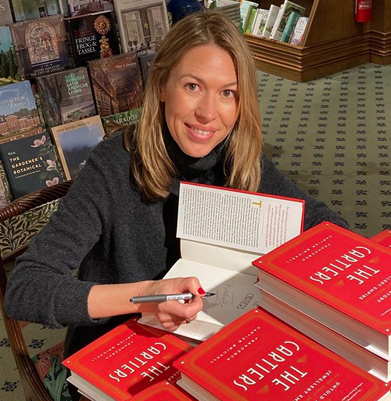 Francesca Cartier Brickell smiles, signing red-covered copies of her book, "The Cartiers.