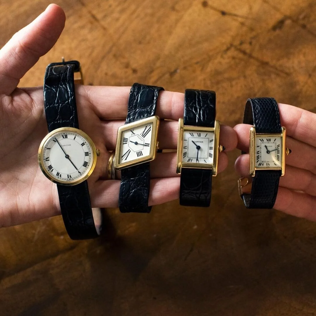 Four vintage gold Cartier watches: round, angled rectangular, and two rectangular, with black straps.