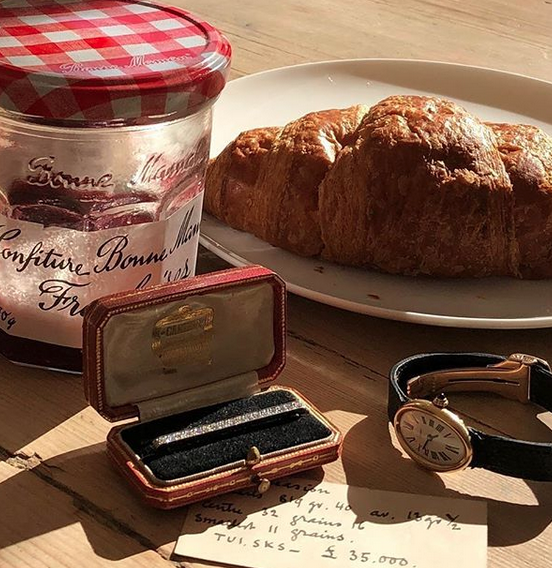 Vintage gold Cartier watch, diamond bar brooch in its red box, with breakfast items.